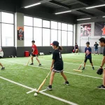 Hitclub training scene with young athletes practicing baseball techniques, showcasing teamwork and motivation.